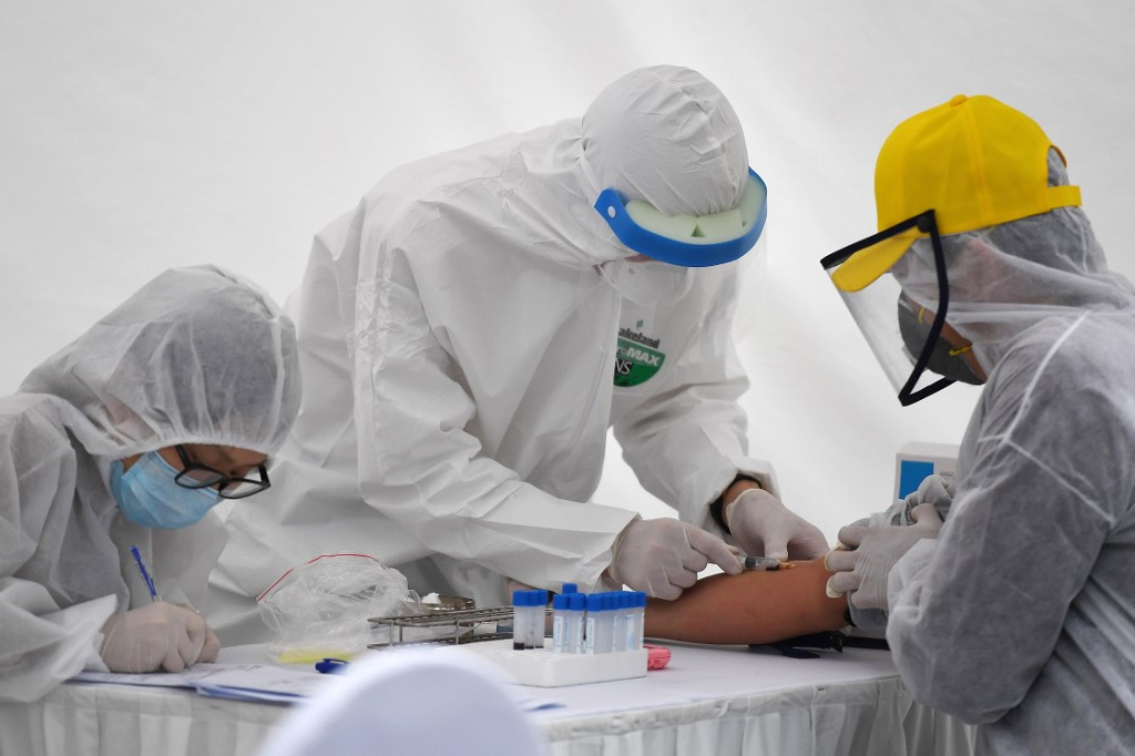 Pekerja medis di Indonesia mengenakan APD tampak sedang mengambil darah seorang pasien